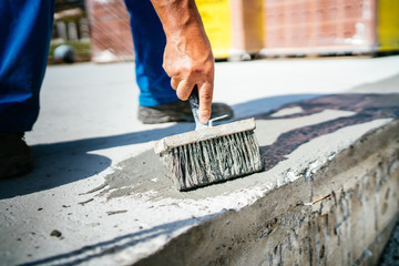 close up details of worker using brush for covering concrete basement with waterproof materials