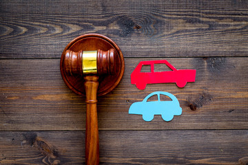 Car accident lawsuit concept. Two collided cars near judge gavel on dark wooden background top view...