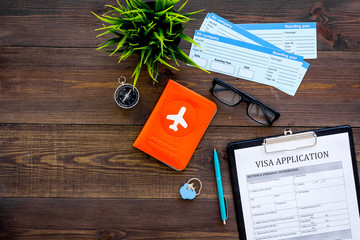 Prepare to trip. Do visa. Airplane tickets near passport cover with airplane silhouette, visa application form, compas on dark wooden background top view copy space