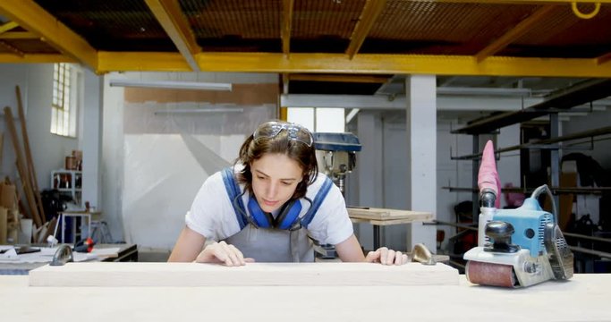 Female welder examining a wooden plank 4k