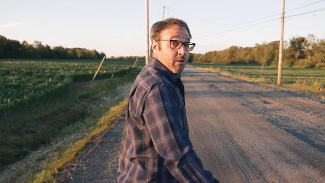Man walking on the side of the road looking behind him every seconds to see if he is followed by somebody. Suspicious behavior