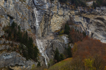 Obraz premium Beautiful autumn time at village of Lauterbrunnen in Swiss alps, gateway to famous Jungfrau. Set in a valley featuring rocky cliffs and the roaring