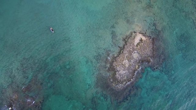 Aerial top view of a boat and a little island in the sea