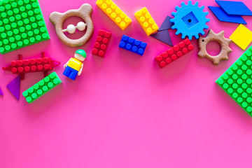 Toys for little children. Plastic bricks and clacks on pink background top view copy space