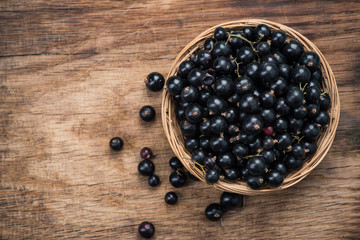 Fresh ripe blackcurrant in basket, copy space on wooden board