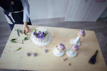 confectioner in a blue apron on a light background with a cake