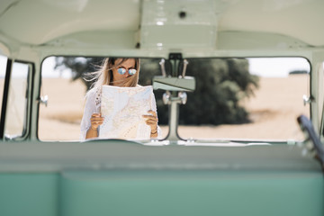 Attractive woman who looks at the map next to her van