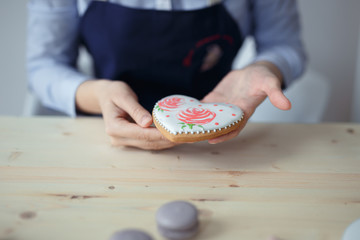 confectioner in a blue apron on a light background with a cake