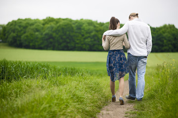 Naklejka na ściany i meble Couple holding hands at the green walk
