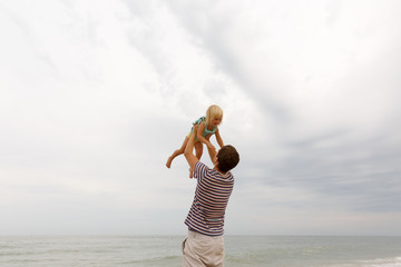Father and daughter.Man throws up  laughing girl with blond hair.