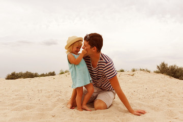 Father and daughter. The man is playing with the child on the beach.