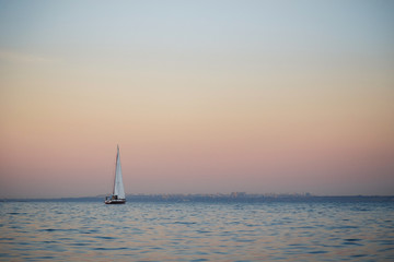Fototapeta na wymiar Nice view of small white sailboat, yacht sailing at sunset