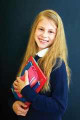 Happy little  school girl near school blackboard