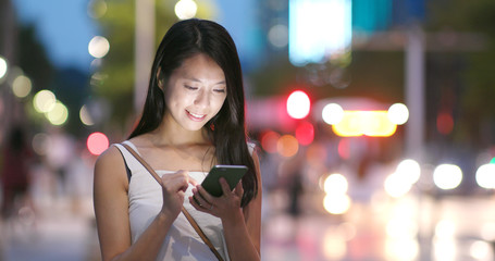 Woman works on mobile phone in city at night