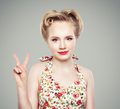 Beautiful retro vintage pin-up girl showing two fingers. Victory hand sing or peace gesture. Young blonde woman with makeup and perfect hairstyle