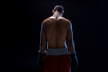 Fototapeta na wymiar A boxer in his shorts stands with his back, his head is lowered. Recreation. Black background