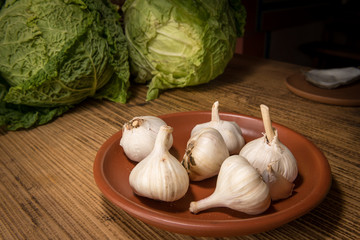 Plate with garlic tubers standing on a wooden table