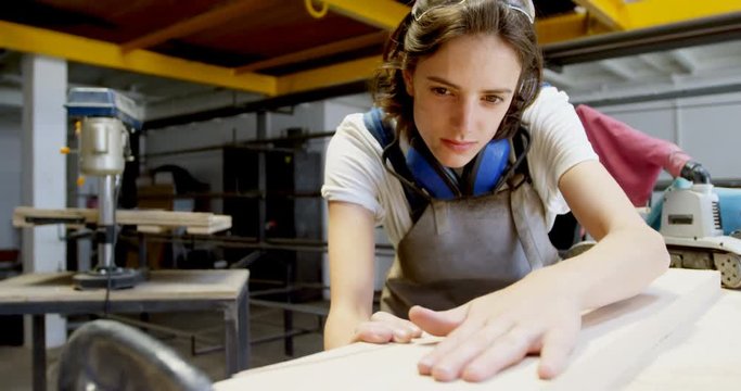 Female welder examining a wooden plank 4k