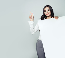 Fototapeta premium Business woman portrait. Businesswoman pointing to empty grey background and holding white banner background. Seo and advertising marketing concept
