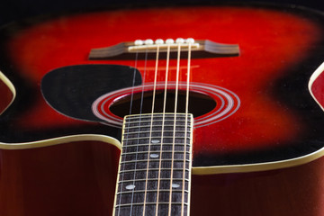 Acoustic red guitar lying on the table in the background with a copy of the hands space playing acoustic guitar, close-up of fretboard and strings, Wallpapers - Powered by Adobe