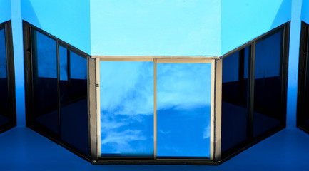 glass window with reflection from the sky at blue concrete building