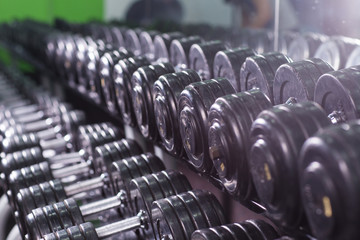 Naklejka na ściany i meble Black dumbbell set in sport fitness center. Weight Training Equipment concept.