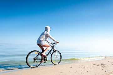 Fototapeta premium Young teenage sporty girl riding bicycle at the seaside