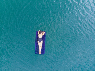 woman on mattress in azure water. overhead view. copy space