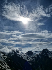 Fototapeta na wymiar Hochformat: Hochgebirge an der Großglockner Hochalpenstraße mit blauem Himmel,dramatischen Wolken und Sonne