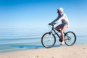 Fototapeta na wymiar Young teenage sporty girl riding bicycle at the seaside