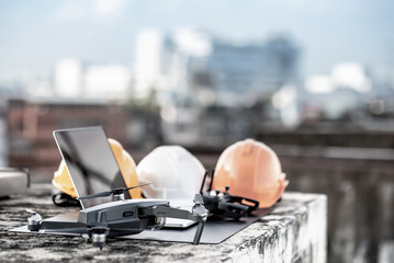 Drone, smartphone, laptop computer and protective helmet at construction site. Using unmanned...