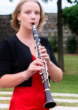junge Frau mit rotem Kleid spielt Klarinette