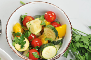 Cherry tomatoes, zucchini, yellow sweet peppers are marinated with garlic, parsley, olive oil, balsamic sauce and lemon juice. View from above. Close-up. Macro photography.