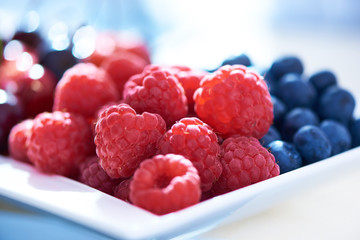Raspberries and blueberries on a blurred background. Close-up.