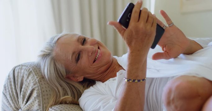 Disabled woman using mobile phone in living room 4k