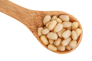 Shelled cedar pine nuts in wooden spoon isolated on white background. Top view. Flat lay