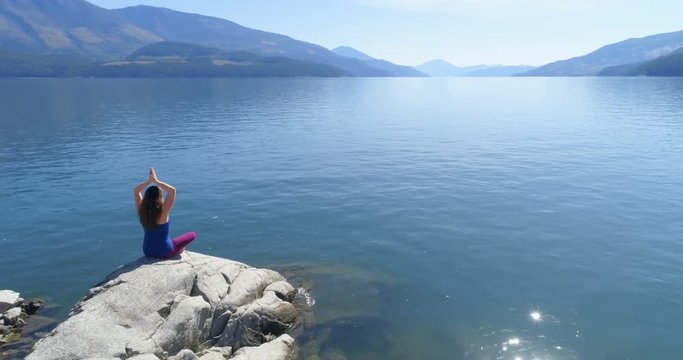 Woman performing yoga on at lake shore 4k