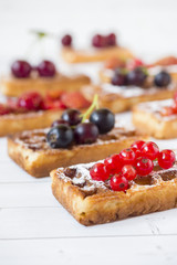 Homemade waffles with summer berries on a light table. Selective focus