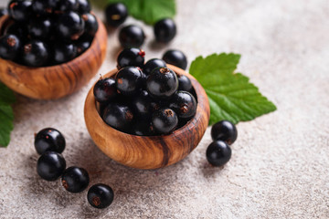 Black currant with leaves in wooden bowls