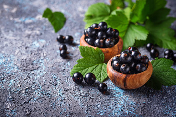 Black currant with leaves in wooden bowls