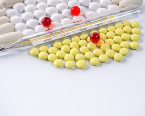 Thermometer on yellow and white tablets lying on a white background
