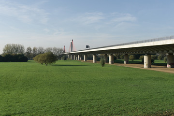 A field with an automobile bridge passing over the river on a summer day