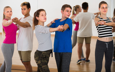 Group of smiling teen dancing tango in dance studio