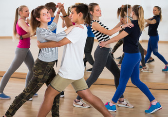 Group of sports teen dancing tango in dance studio