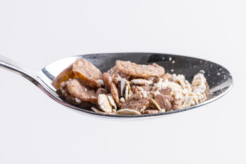 Chocolate muesli on a silver spoon isolated on white