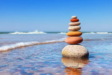Foto op Canvas Rock zen-piramide van kleurrijke kiezelstenen die in het water op de achtergrond van de zee staan. Concept van evenwicht, harmonie en meditatie. © Aleksandr Simonov