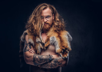 Naked tattoed redhead hipster male with long luxuriant hair and full beard posing with the fox...