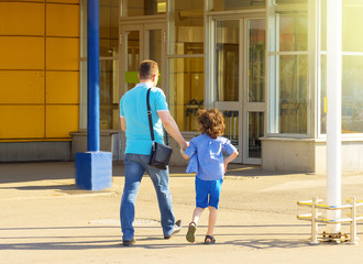 Dad and son going shopping in the supermarket. They are at an entrance to a mega shopping center.