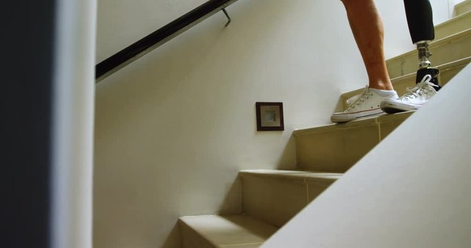 Mature woman with prosthetic leg moving down from stairs 4k