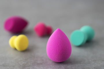 Multicolored cosmetic sponges on a gray concrete background.